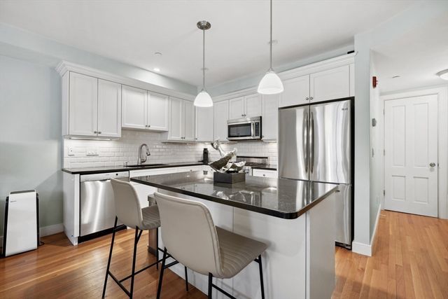 a kitchen with stainless steel appliances granite countertop a refrigerator a stove a sink dishwasher a refrigerator and white cabinets with wooden floor