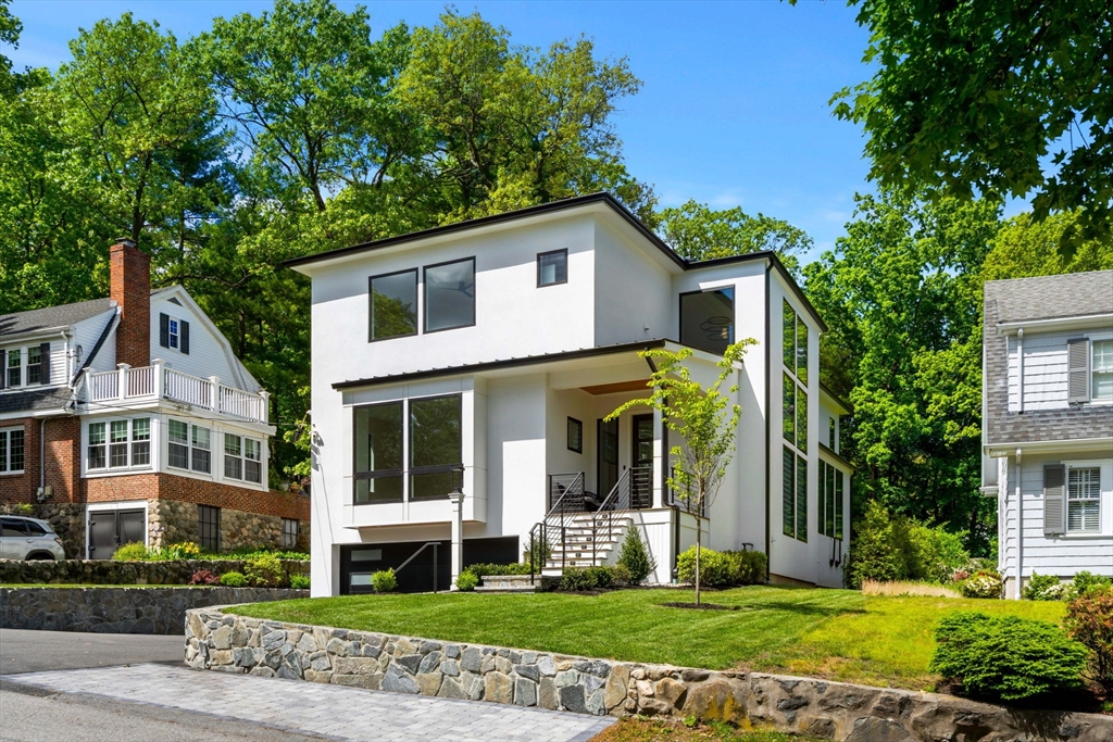 a view of a white house with a big yard and potted plants and large trees