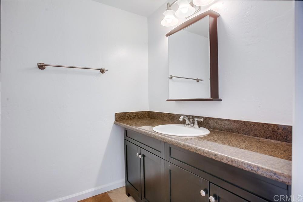 1295 Prospect Street, Unit D La Jolla, CA 92037 - Photo 17 of 24 a bathroom with a granite countertop sink and a mirror