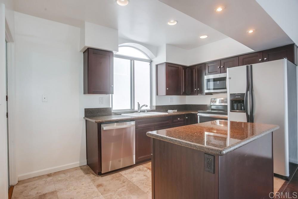 1295 Prospect Street, Unit D La Jolla, CA 92037 - Photo 8 of 24 a kitchen with stainless steel appliances granite countertop a sink a stove a refrigerator a center island and a refrigerator