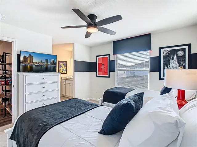 a bedroom with a bed a dresser and a large window