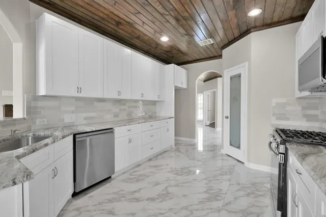 a kitchen with stainless steel appliances granite countertop a sink a stove and a microwave