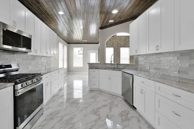 a kitchen with granite countertop white cabinets white stainless steel appliances and a sink