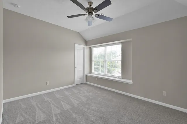 an empty room with a window and a fan