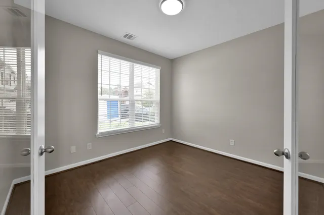 an empty room with wooden floor and windows