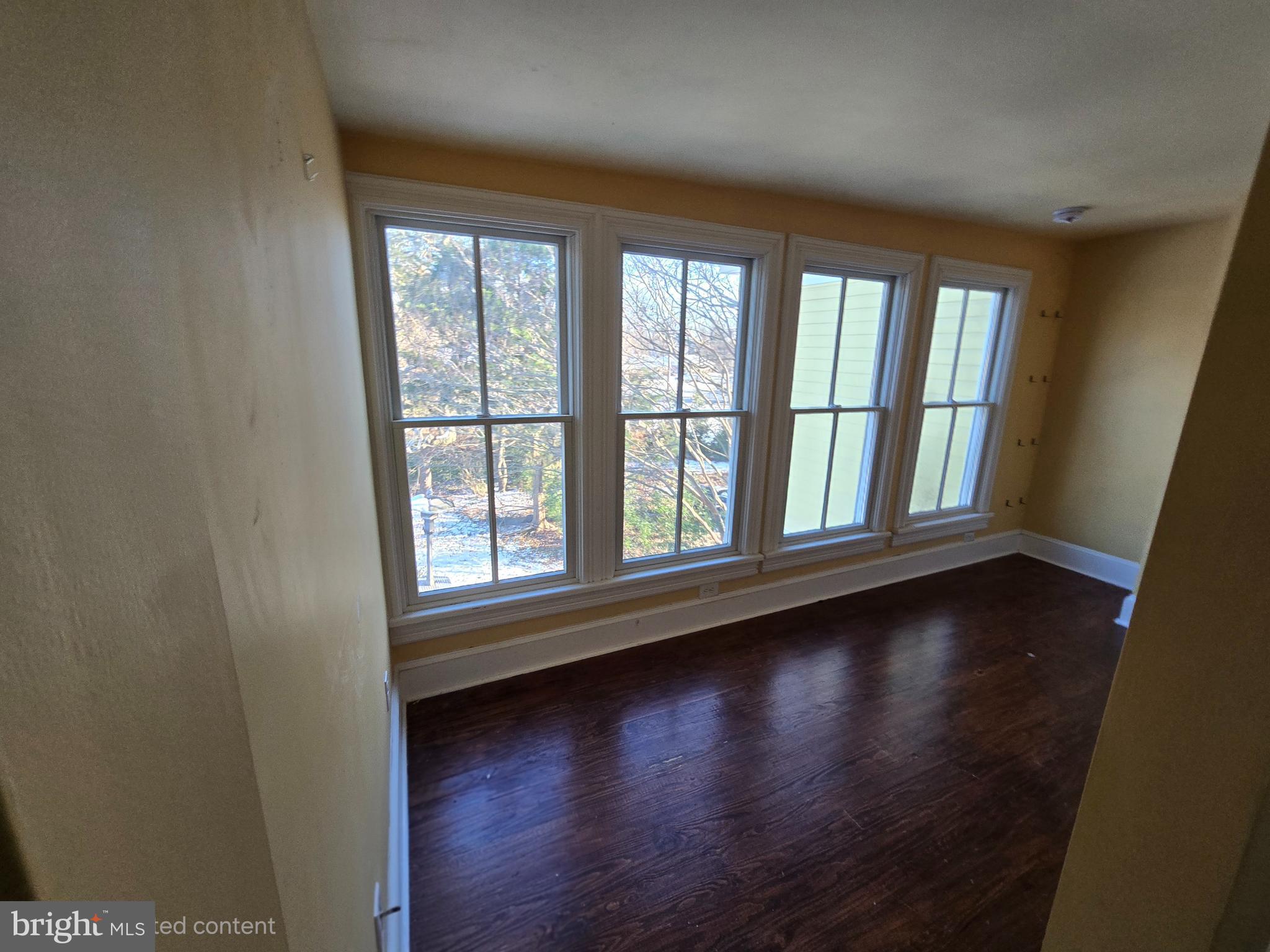 101 Chapel Road Easton, MD 21601 - Photo 8 of 35 an empty room with wooden floor and windows with curtains
