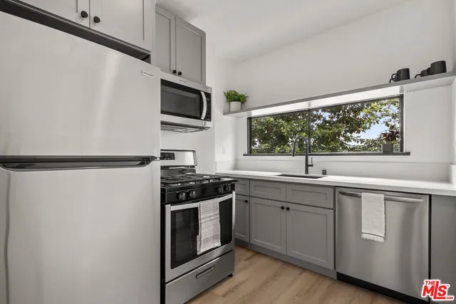 a kitchen with stainless steel appliances a sink cabinets and a window