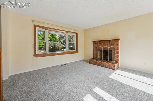 a view of an empty room with a fireplace and a window