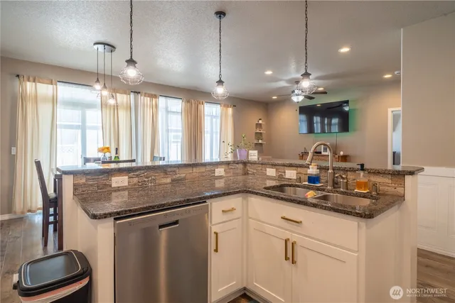 a kitchen with kitchen island granite countertop a sink a counter space appliances and a window