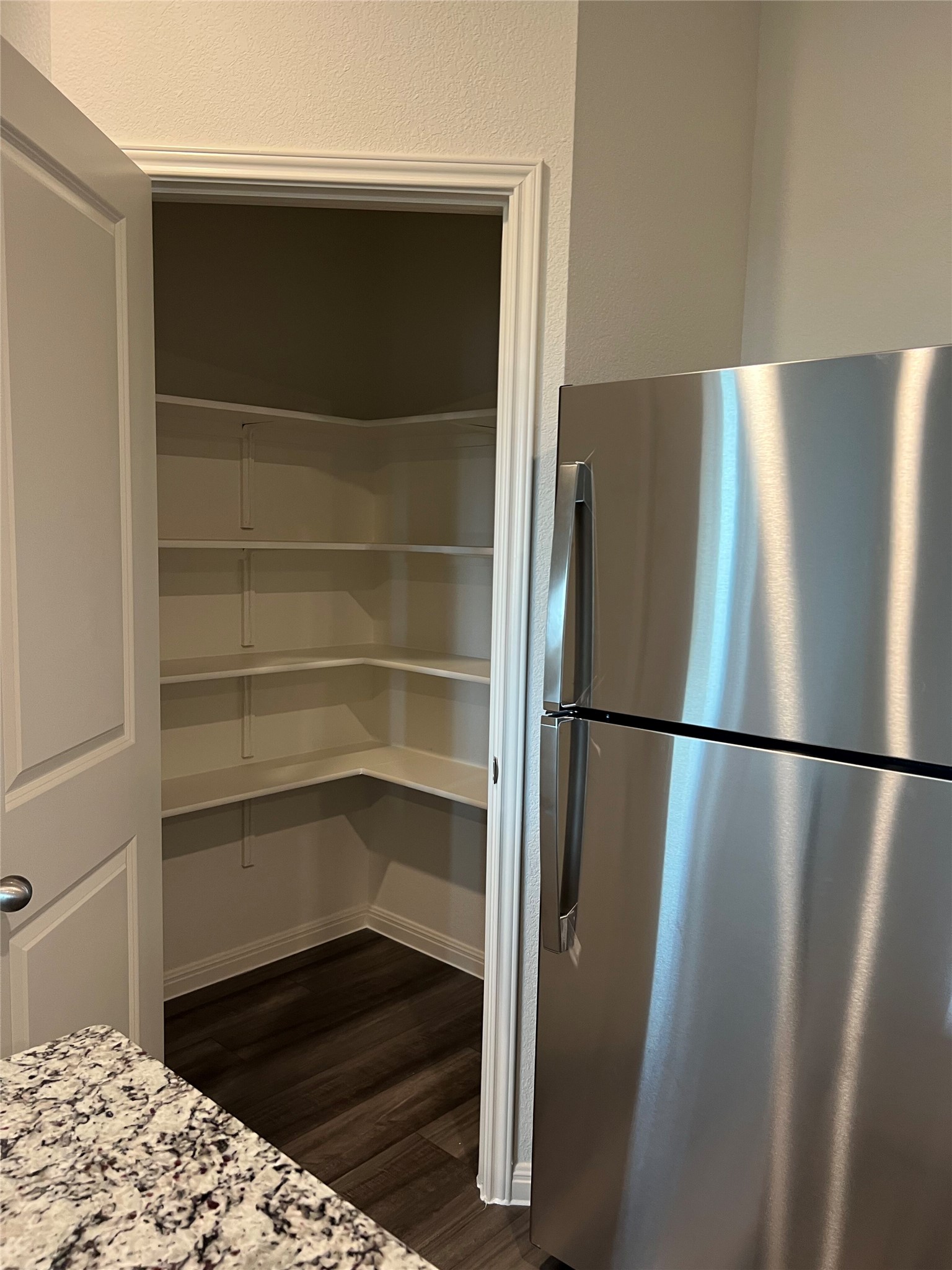 124 Rother Place Taylor, TX 76574 - Photo 8 of 12 Ample storage awaits within this kitchen, featuring a spacious pantry and modern refrigerator.