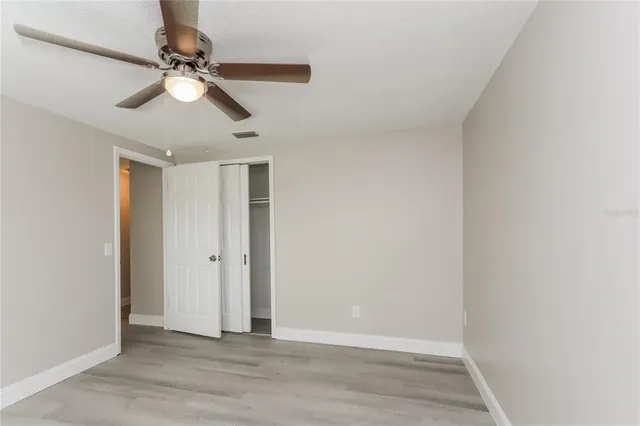 a view of empty room with wooden floor and fan