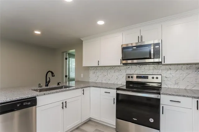 a kitchen with granite countertop a sink and stainless steel appliances