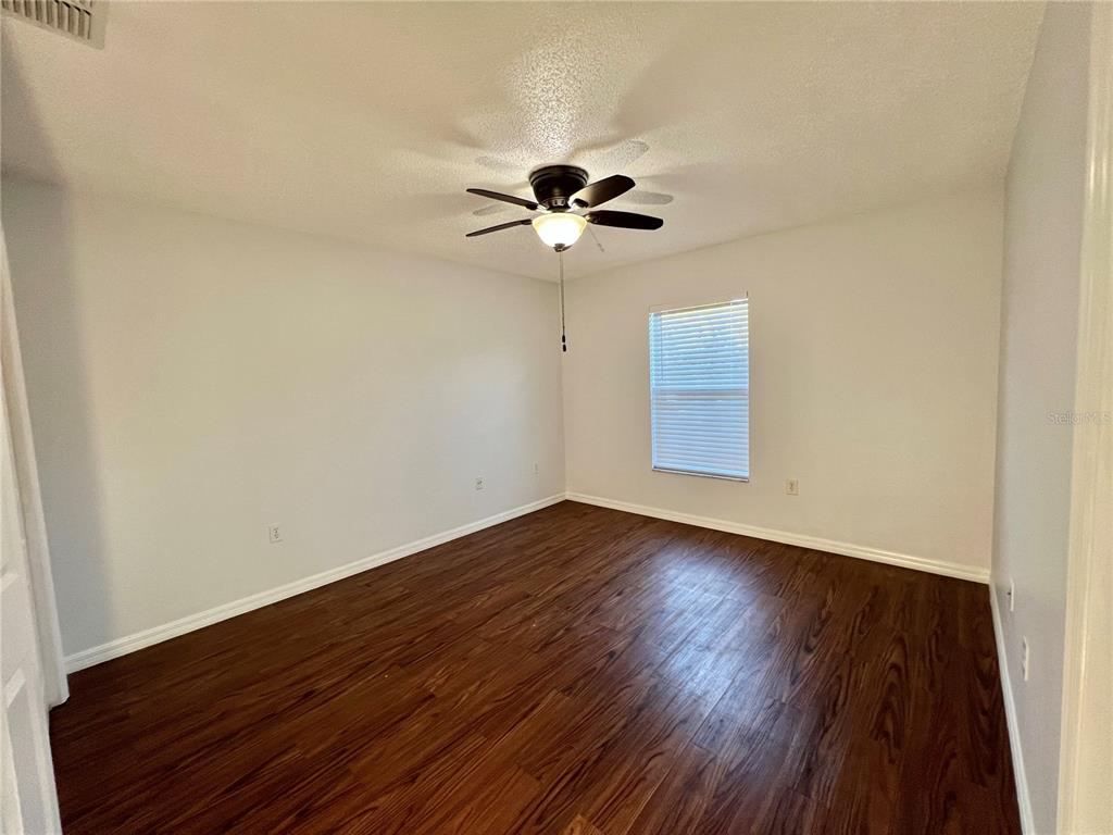 7469 Pond Circle Spring Hill, FL 34606 - Photo 16 of 22 a view of an empty room with a window and wooden floor