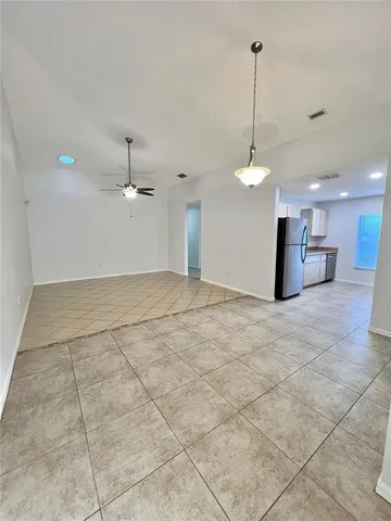 a view of an empty room and a chandelier fan
