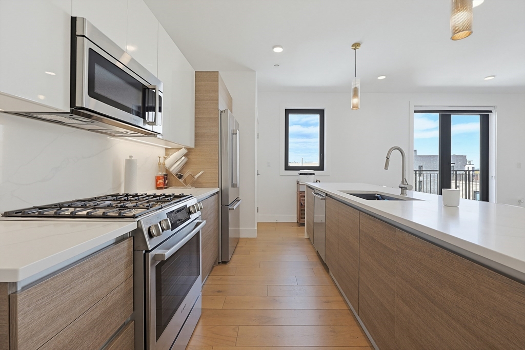 30 Penniman Road, Unit 605 Boston, MA 02134 - Photo 3 of 19 a kitchen with stainless steel appliances granite countertop a stove a sink and a microwave