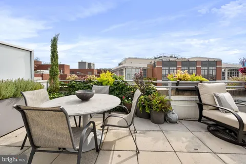 a roof deck with table and chairs and potted plants