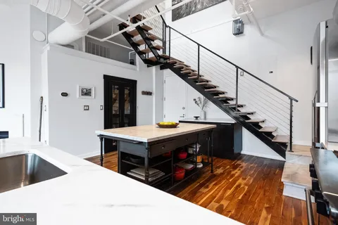 a living room with wooden floor pool table and a refrigerator