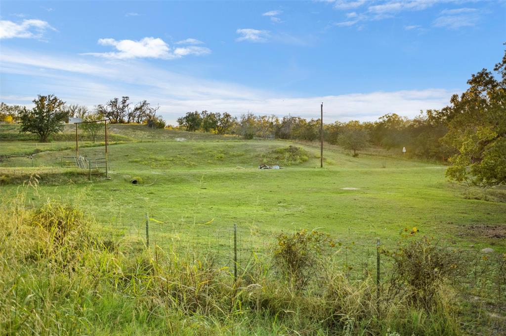 199 Cheyenne Trail Springtown, TX 76082 - Photo 5 of 22 Expansive green field featuring varied terrain, mature trees outlining the perimeter, and a partial wire fence