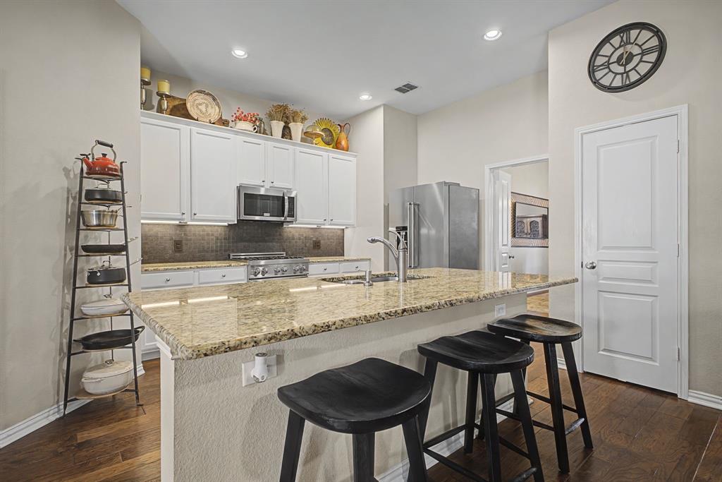 505 Scenic Ranch Circle Fairview, TX 75069 - Photo 9 of 32 a kitchen with granite countertop a table chairs stove and cabinets