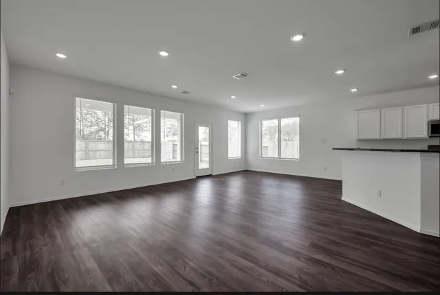 an empty room with wooden floor and windows