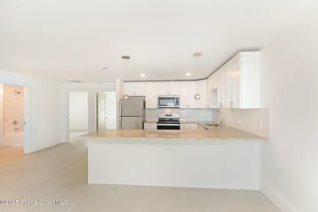 a large white kitchen with kitchen island a stove a sink a refrigerator and white cabinets