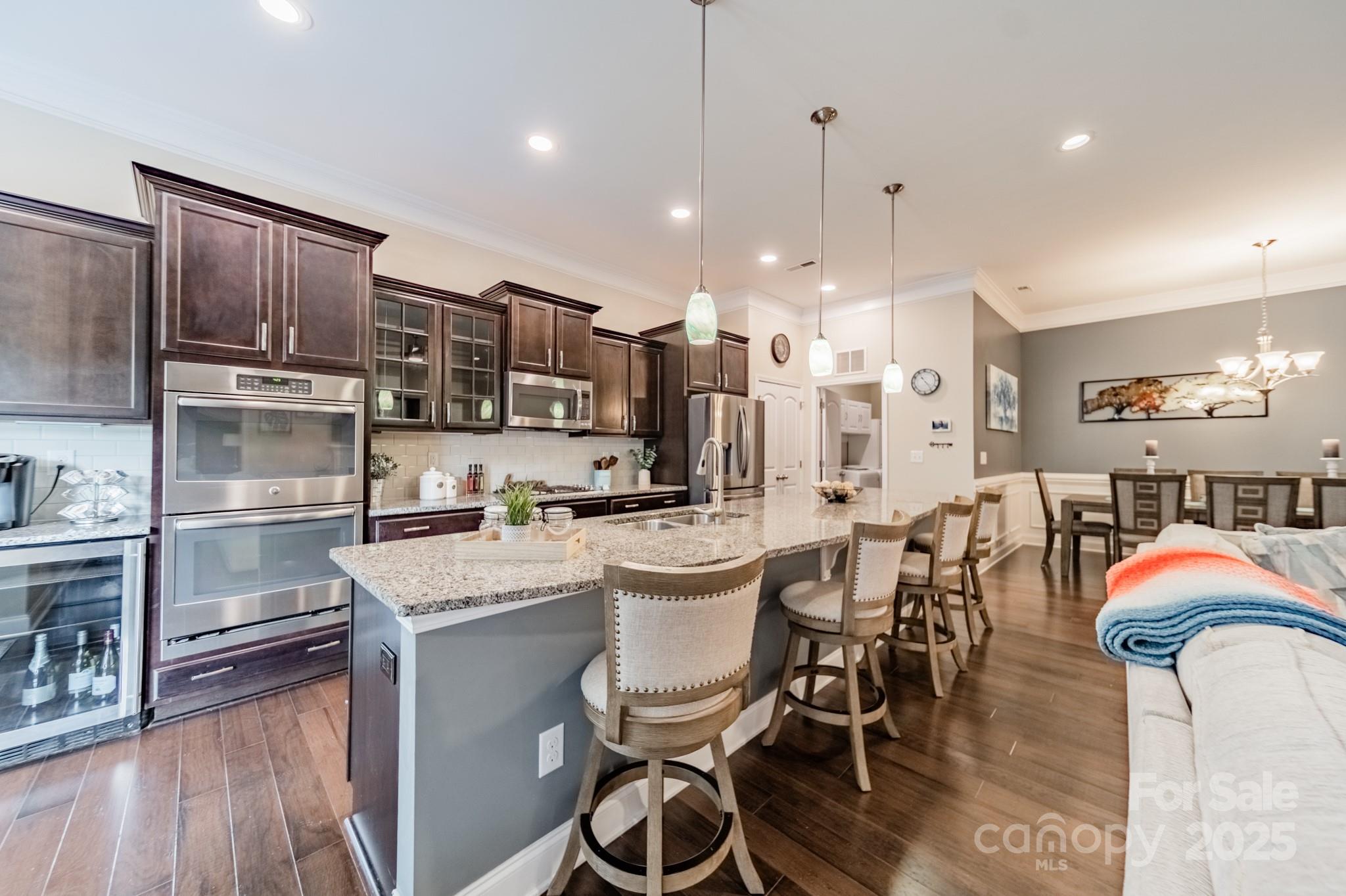 3419 Streamside Drive, Unit 463 Davidson, NC 28036 - Photo 5 of 43 a kitchen with stainless steel appliances a dining table chairs stove refrigerator and cabinets
