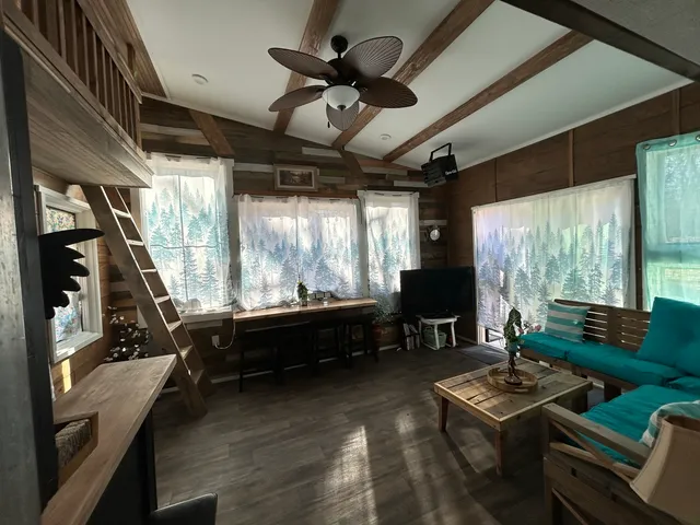 a living room with furniture a flat screen tv and a large window
