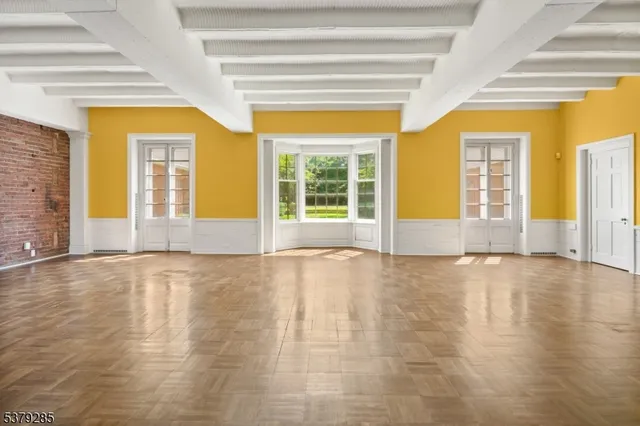 a view of an empty room with window and a kitchen