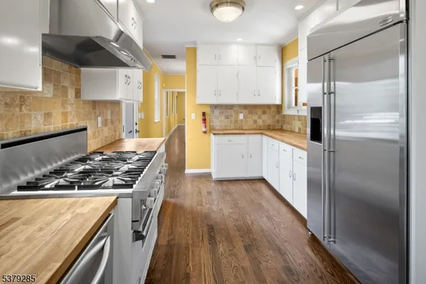 a kitchen with a refrigerator a sink and wooden floor