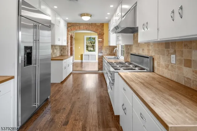 a kitchen with kitchen island granite countertop a sink a refrigerator and wooden floor