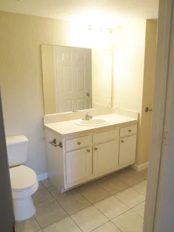 a spacious bathroom with a granite countertop sink toilet and mirror