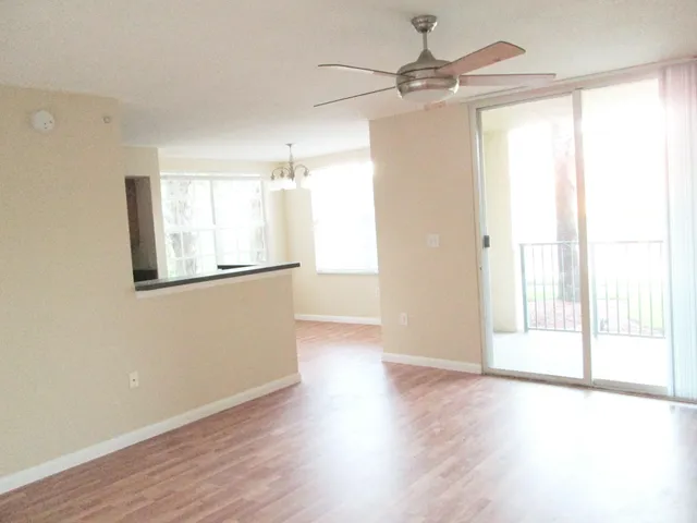 an empty room with wooden floor fan and windows
