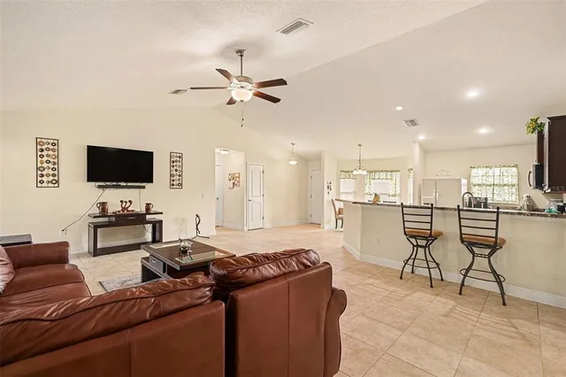 a living room with furniture and a flat screen tv with kitchen view