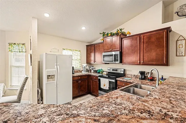 a kitchen with stainless steel appliances granite countertop a refrigerator stove and sink