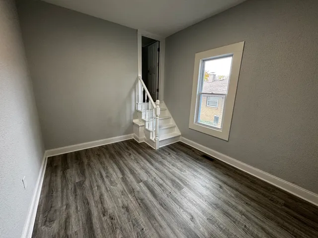 an empty room with wooden floor cabinet and windows