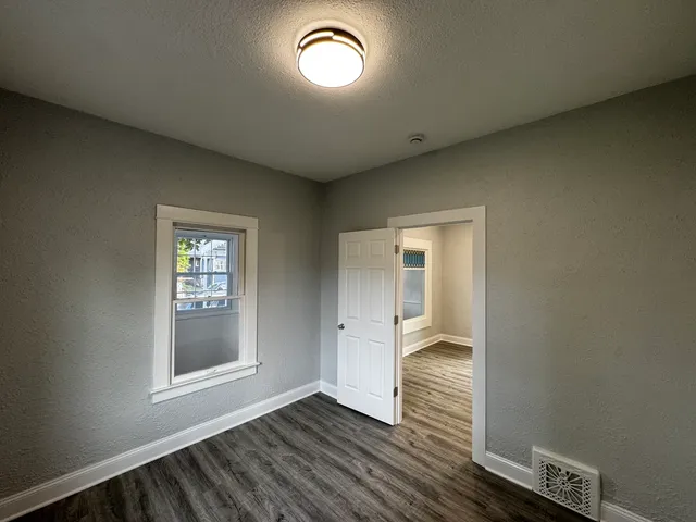 an empty room with wooden floor and windows