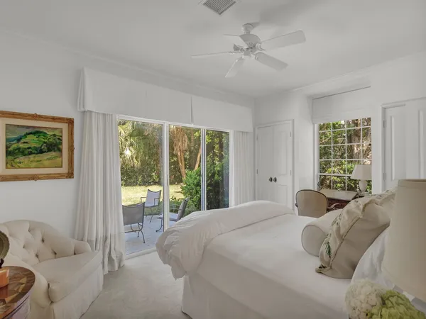 a bedroom with a bed a large window with table and chairs
