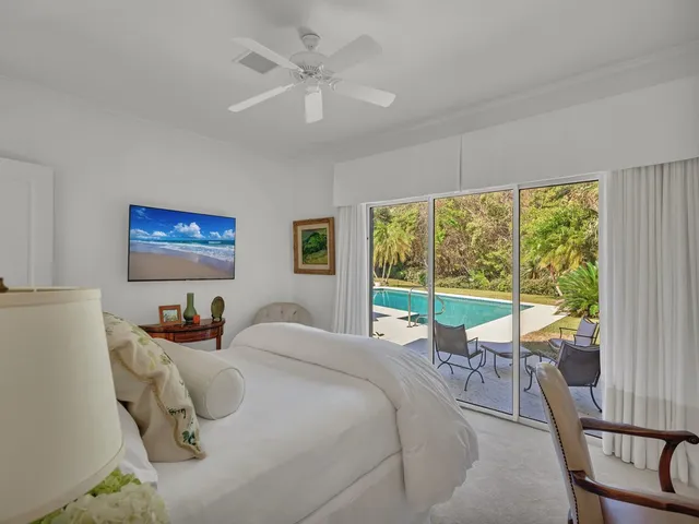 a bedroom with a bed a large window with table and chairs