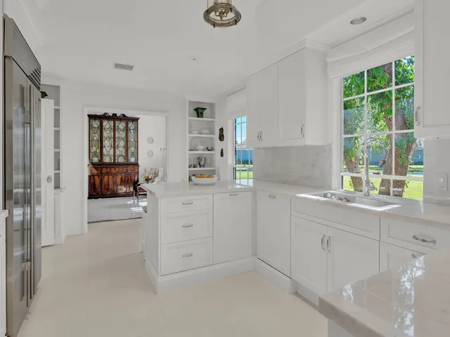 a kitchen with white cabinets and window