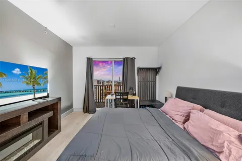 a bedroom with a bed and a flat tv screen on a dresser