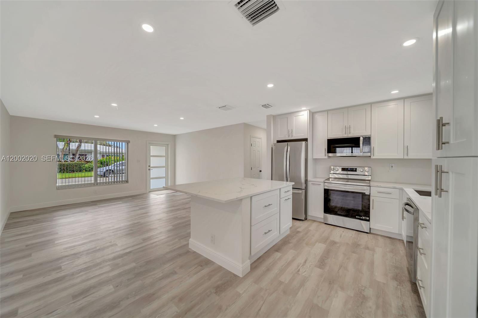 8502 Northwest 59th Street Tamarac, FL 33321 - Photo 5 of 18 a open kitchen with cabinets a sink and a stove top oven with wooden floor