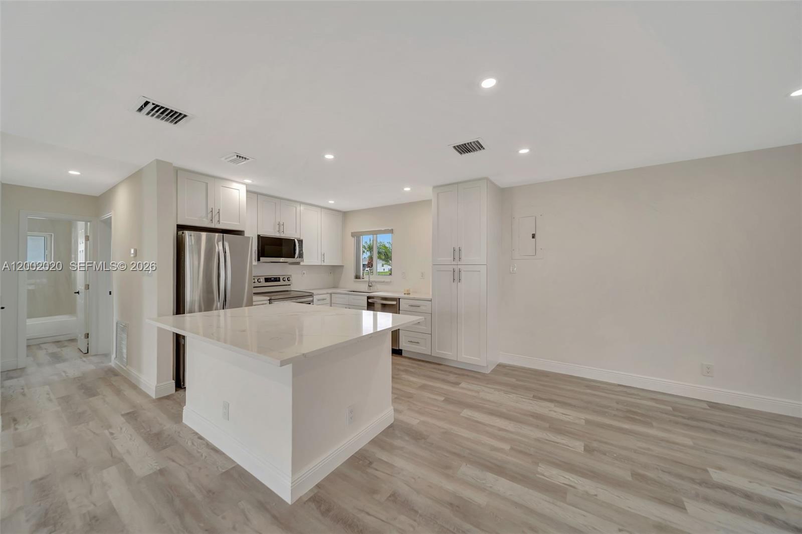 8502 Northwest 59th Street Tamarac, FL 33321 - Photo 8 of 18 a large white kitchen with wooden floor and a refrigerator