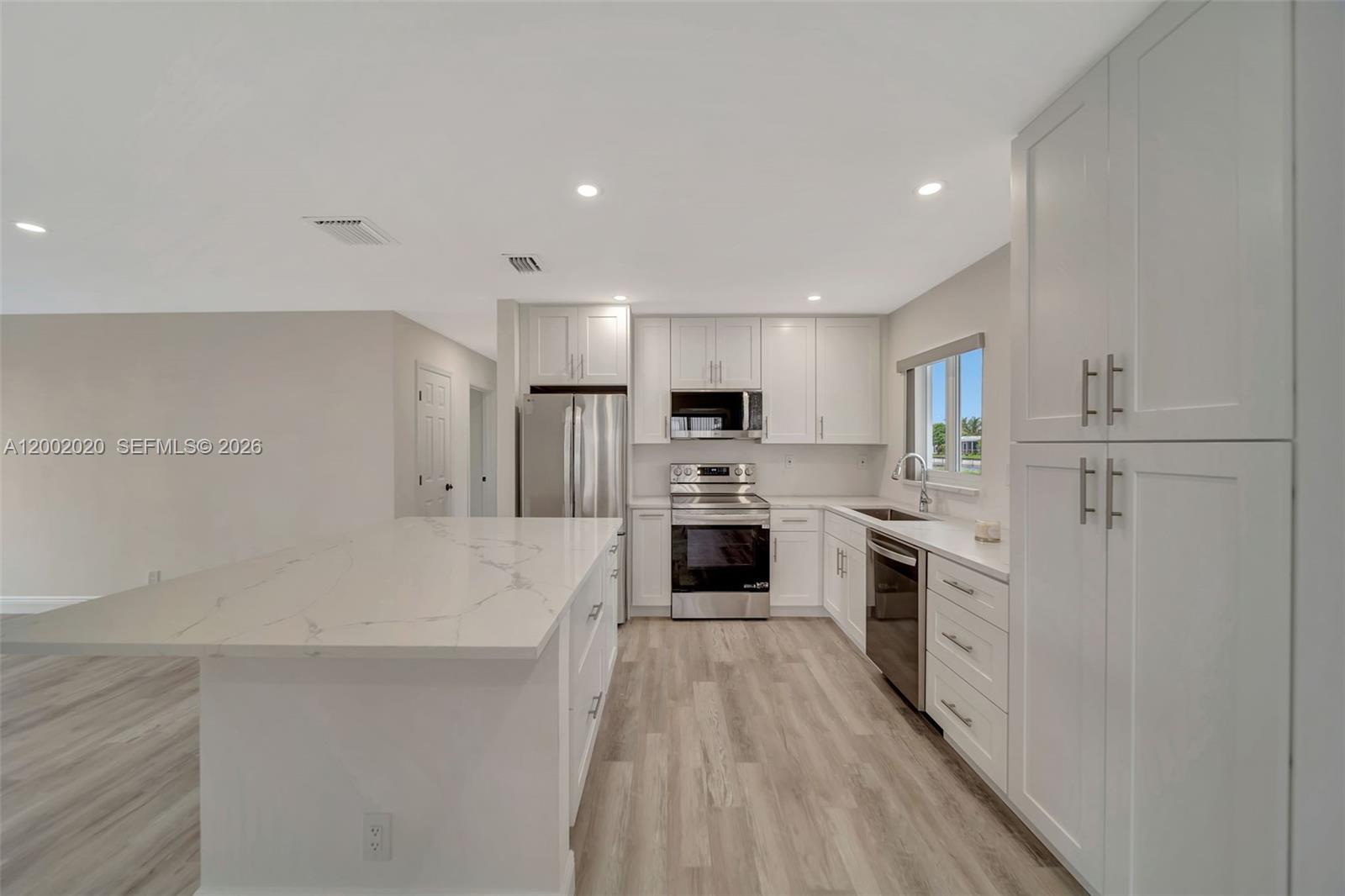 8502 Northwest 59th Street Tamarac, FL 33321 - Photo 9 of 18 a kitchen with white cabinets and stainless steel appliances