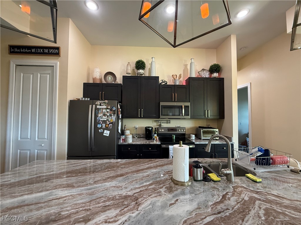 338 Partridge Street Lehigh Acres, FL 33974 - Photo 12 of 30 a kitchen with stainless steel appliances granite countertop a refrigerator a stove and a sink with granite countertops