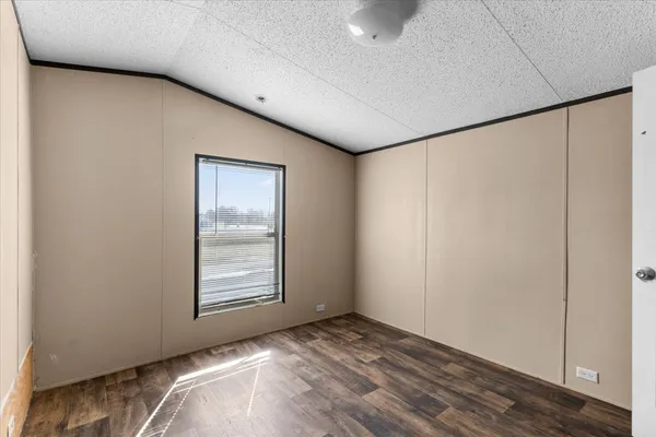 an empty room with wooden floor closet and windows