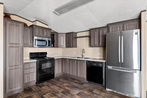 a kitchen with stainless steel appliances kitchen island granite countertop a refrigerator a stove a sink dishwasher and a dining table with garden view