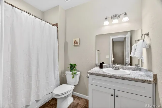 a bathroom with a granite countertop toilet sink and mirror