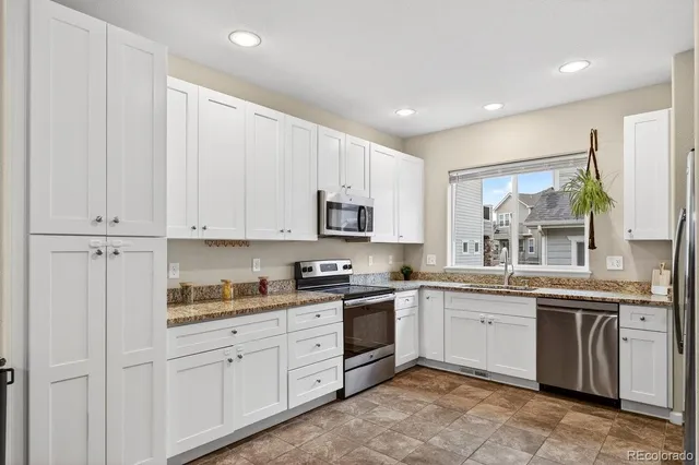 a kitchen with white cabinets sink and appliances
