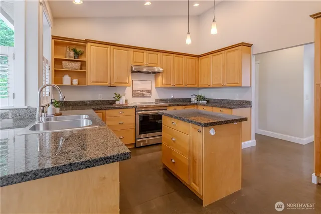 a kitchen with stainless steel appliances granite countertop a sink a stove and a refrigerator