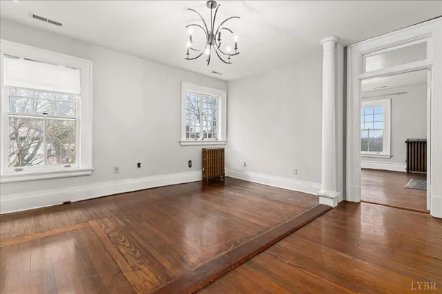 a view of an empty room with window and wooden floor
